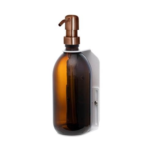 White wall mounted soap dispenser amber bottle and copper pump