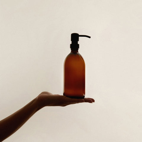 Amber glass soap dispenser in a palm of a hand