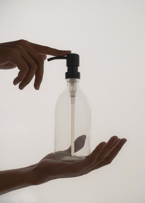 Clear glass soap dispenser being held in hands