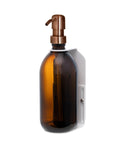 White wall mounted soap dispenser amber bottle and copper pump