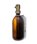 White wall mounted soap dispenser amber bottle and gold pump